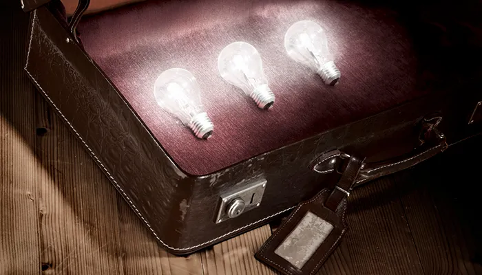 Three lit bulbs resting in an open leather briefcase