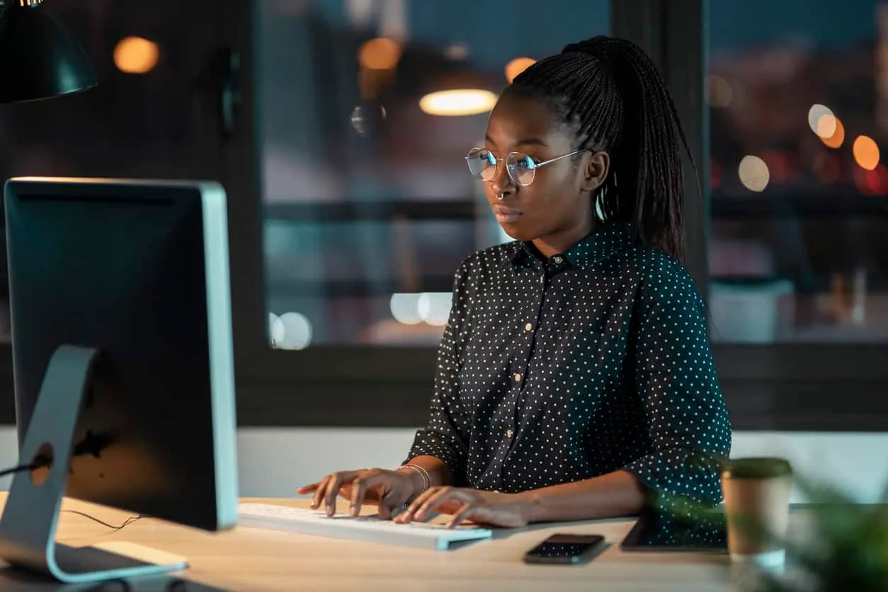 A woman working at a desktop computer in an office at night