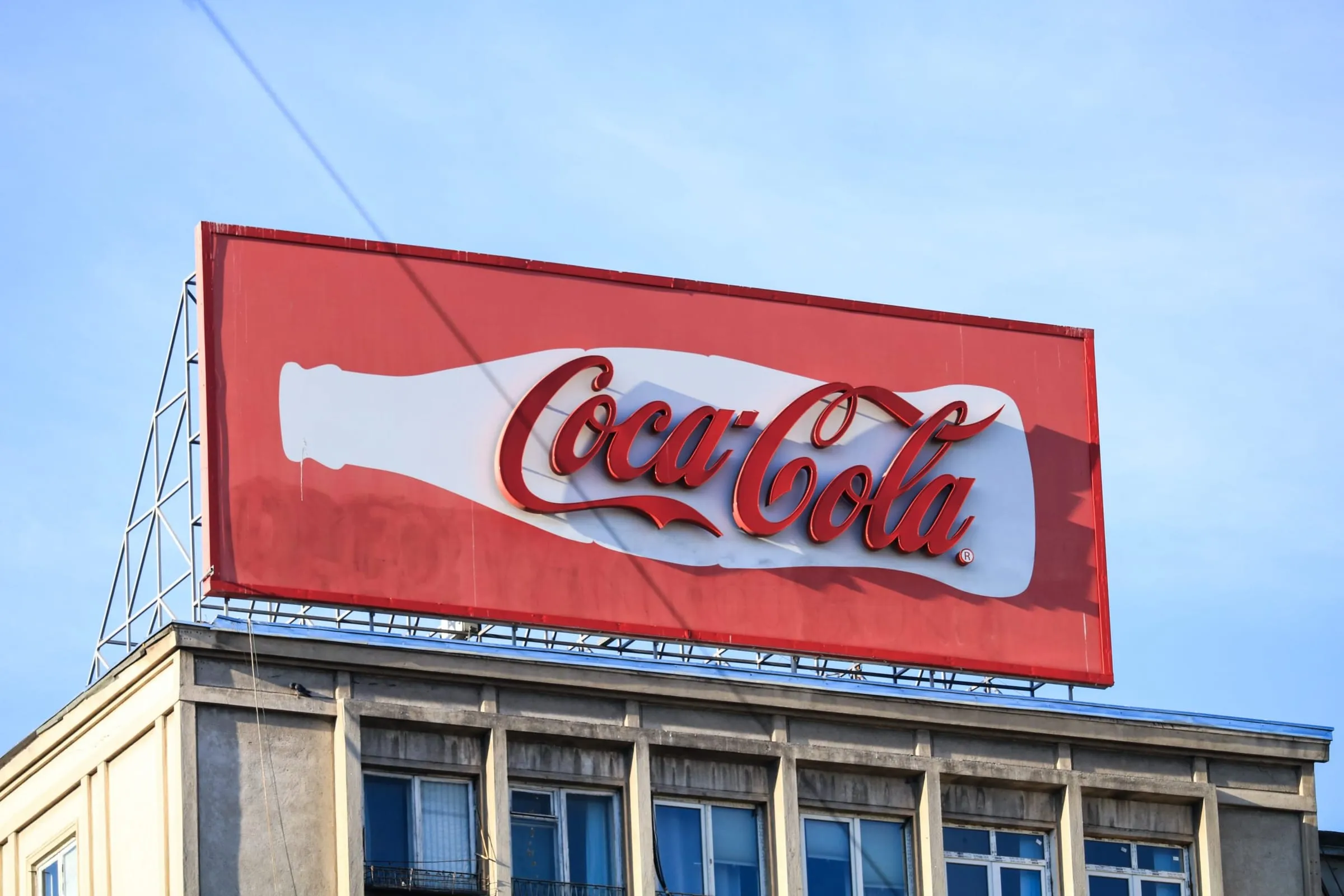 A Coca-Cola billboard on a rooftop against a blue sky