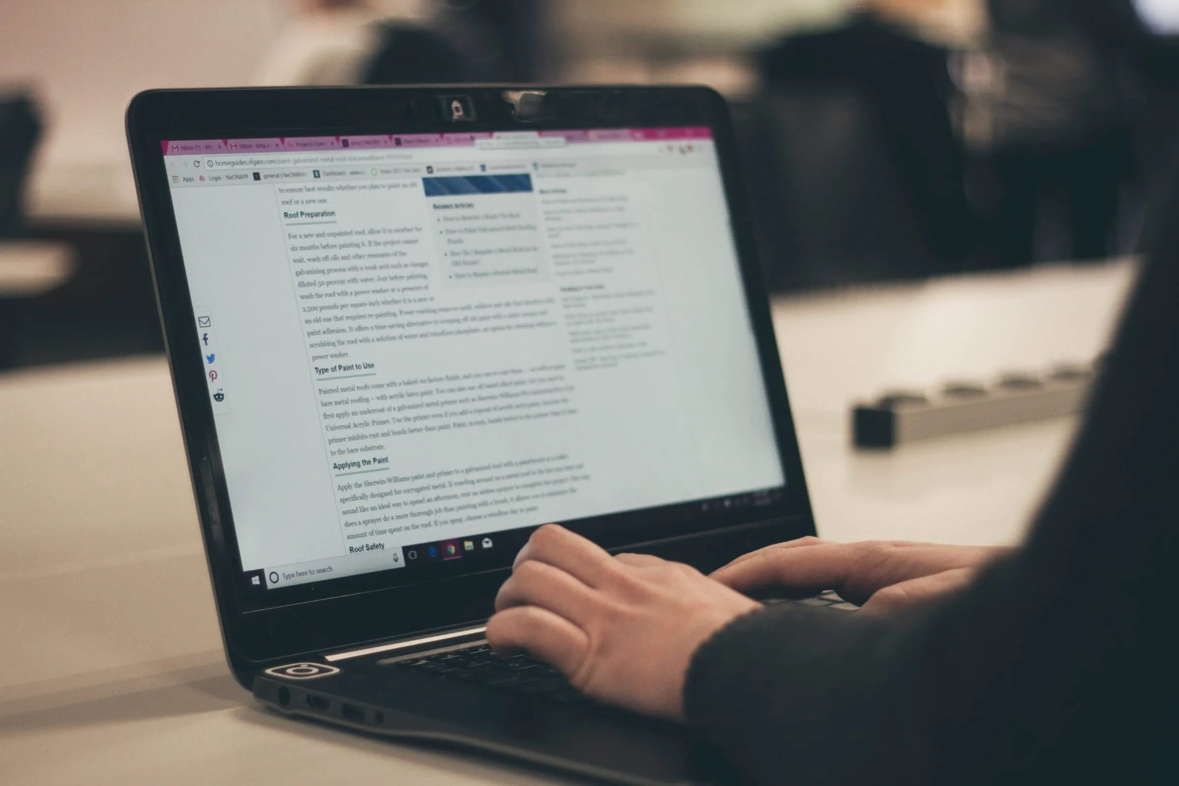 Hands typing on a laptop showing a long article