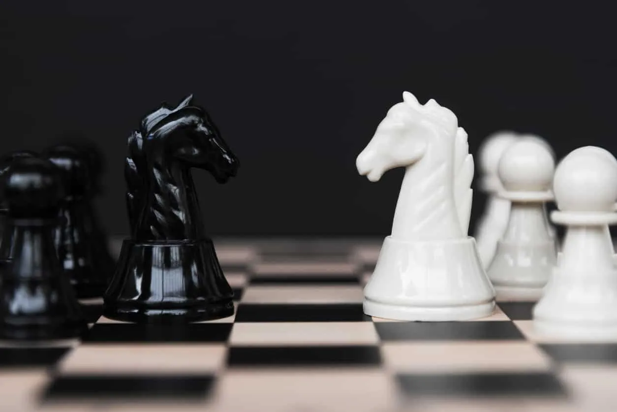 Black and white chess pieces facing each other across a board