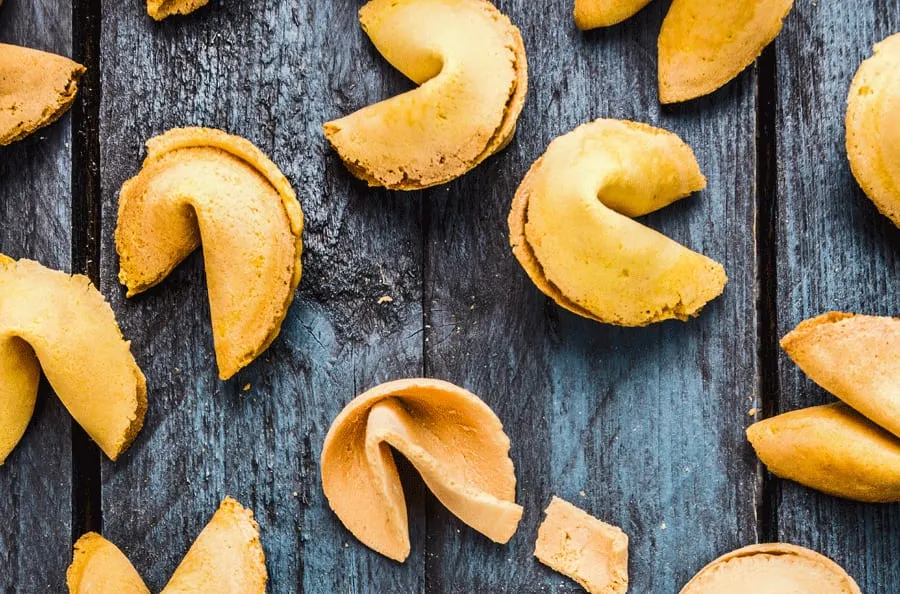 Fortune cookies scattered across a dark wooden surface