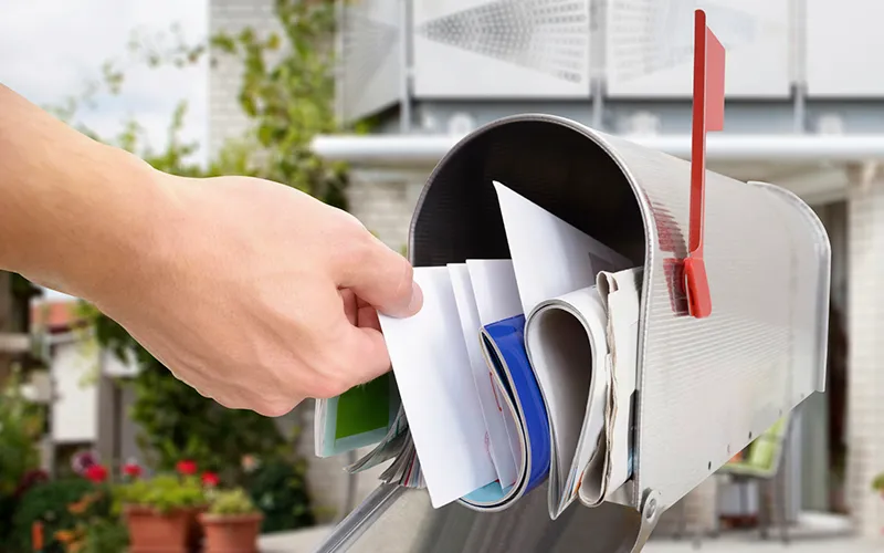 A hand pulling letters out of a roadside mailbox