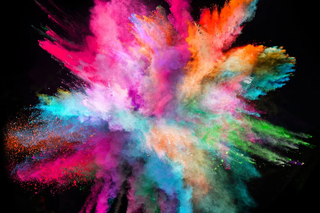 An explosion of brightly coloured powder against a black background