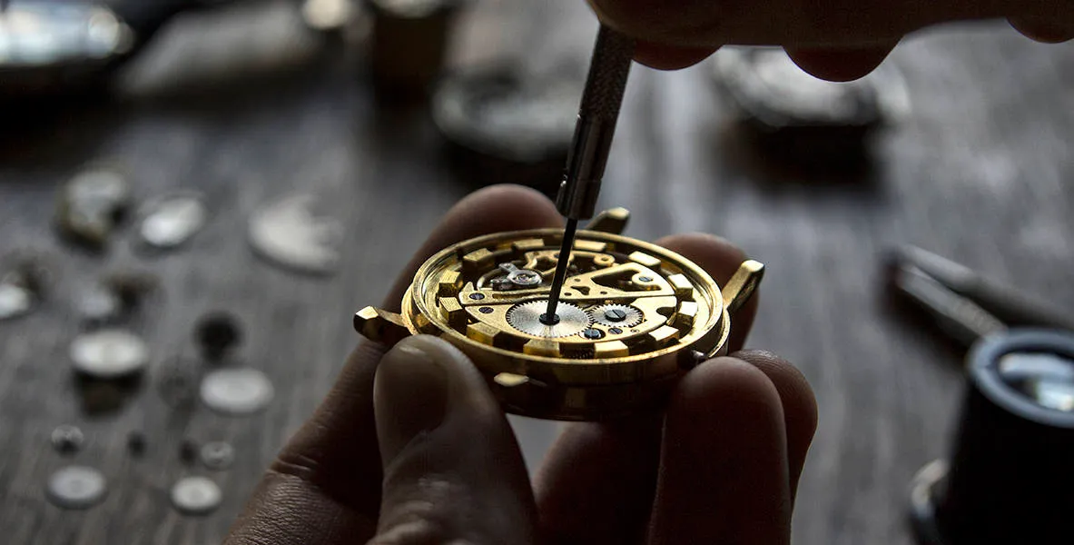 A watchmaker adjusting the movement of a pocket watch with a fine tool