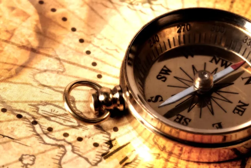 A brass compass resting on an old paper map