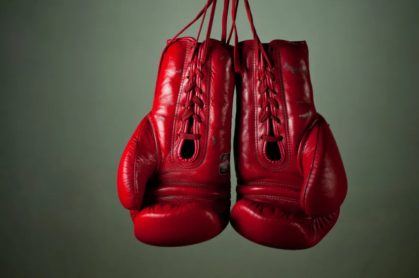 A pair of red boxing gloves hanging by their laces