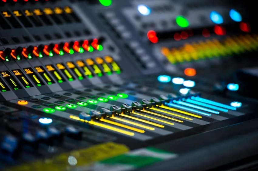 Close view of the lit faders and buttons on an audio mixing desk