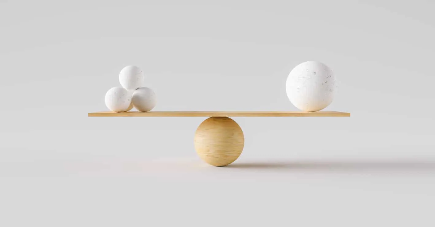 Three small spheres on one end of a wooden seesaw balancing one larger sphere on the other