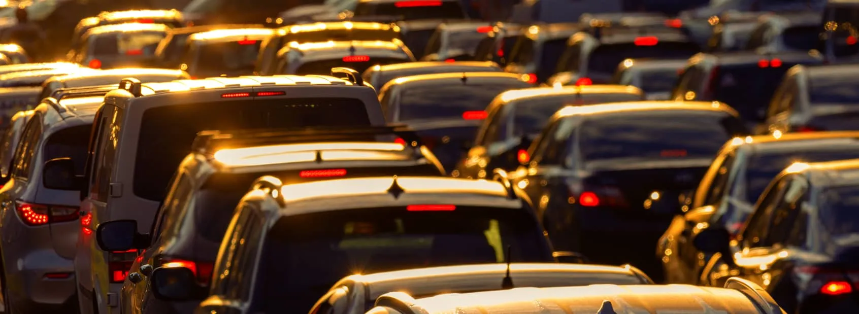 Rows of parked cars at dusk with their tail lights lit