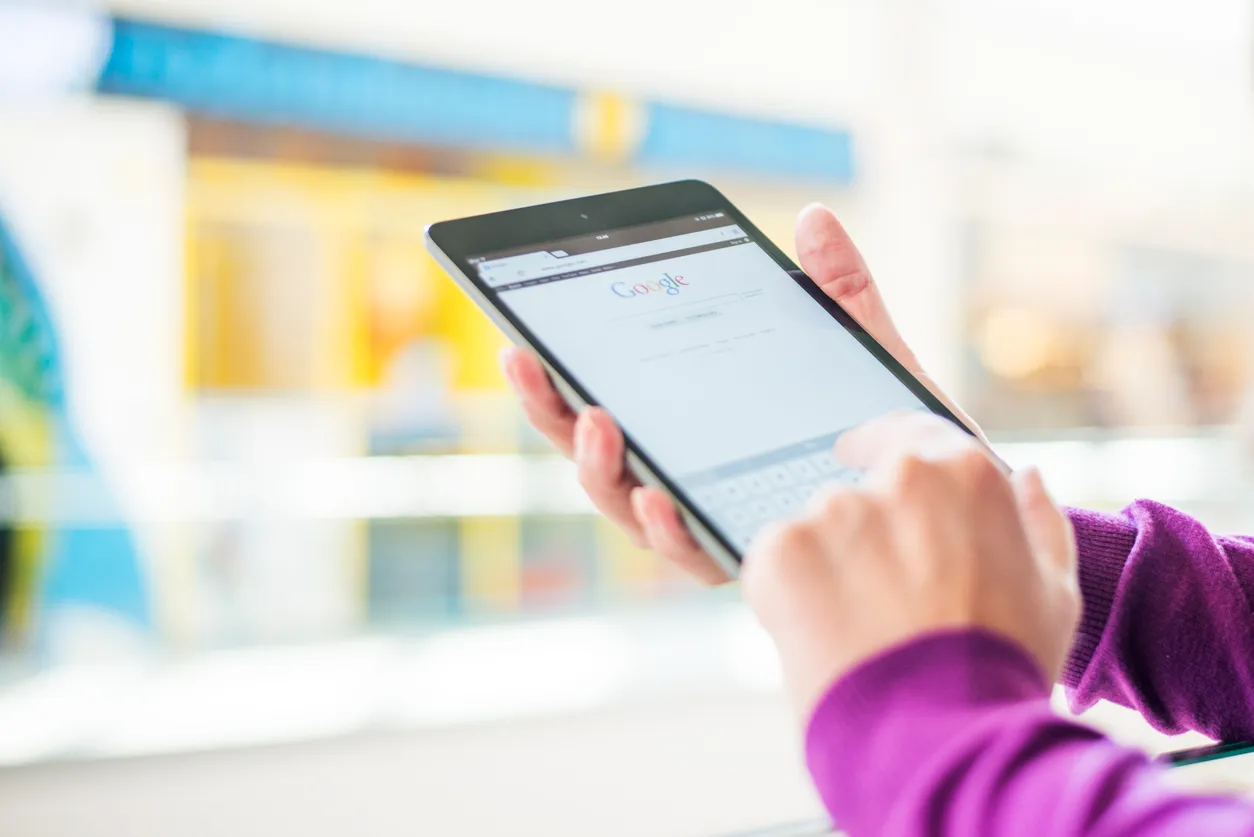 A person using the Google search page on a tablet
