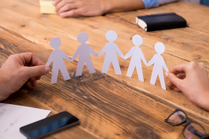 Two people at a table holding a paper chain of cut-out figures