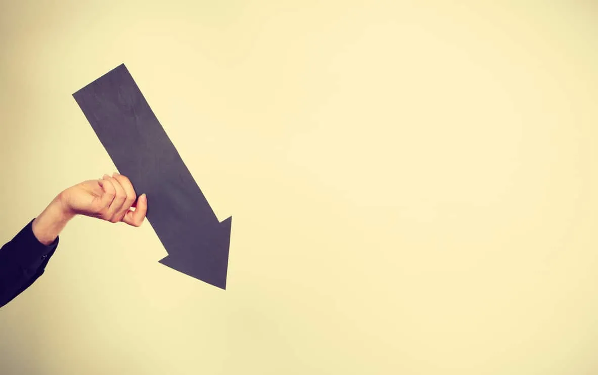 A hand holding a large paper arrow pointing down