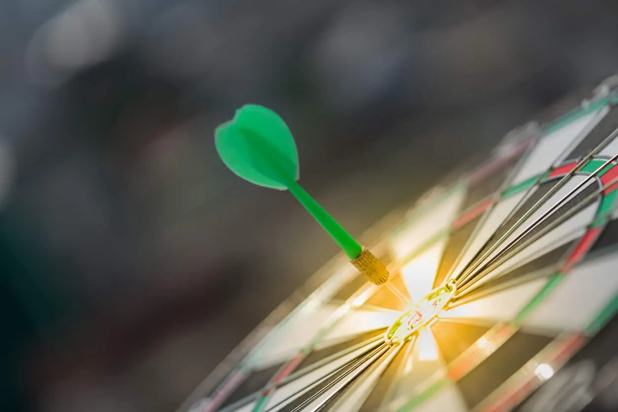 A green dart in the bullseye of a dartboard