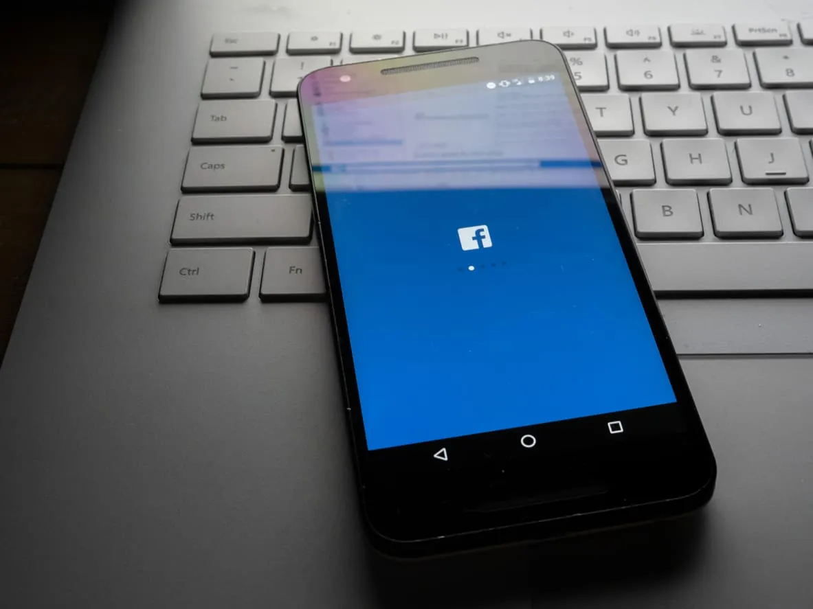 A phone showing the Facebook app resting on a keyboard
