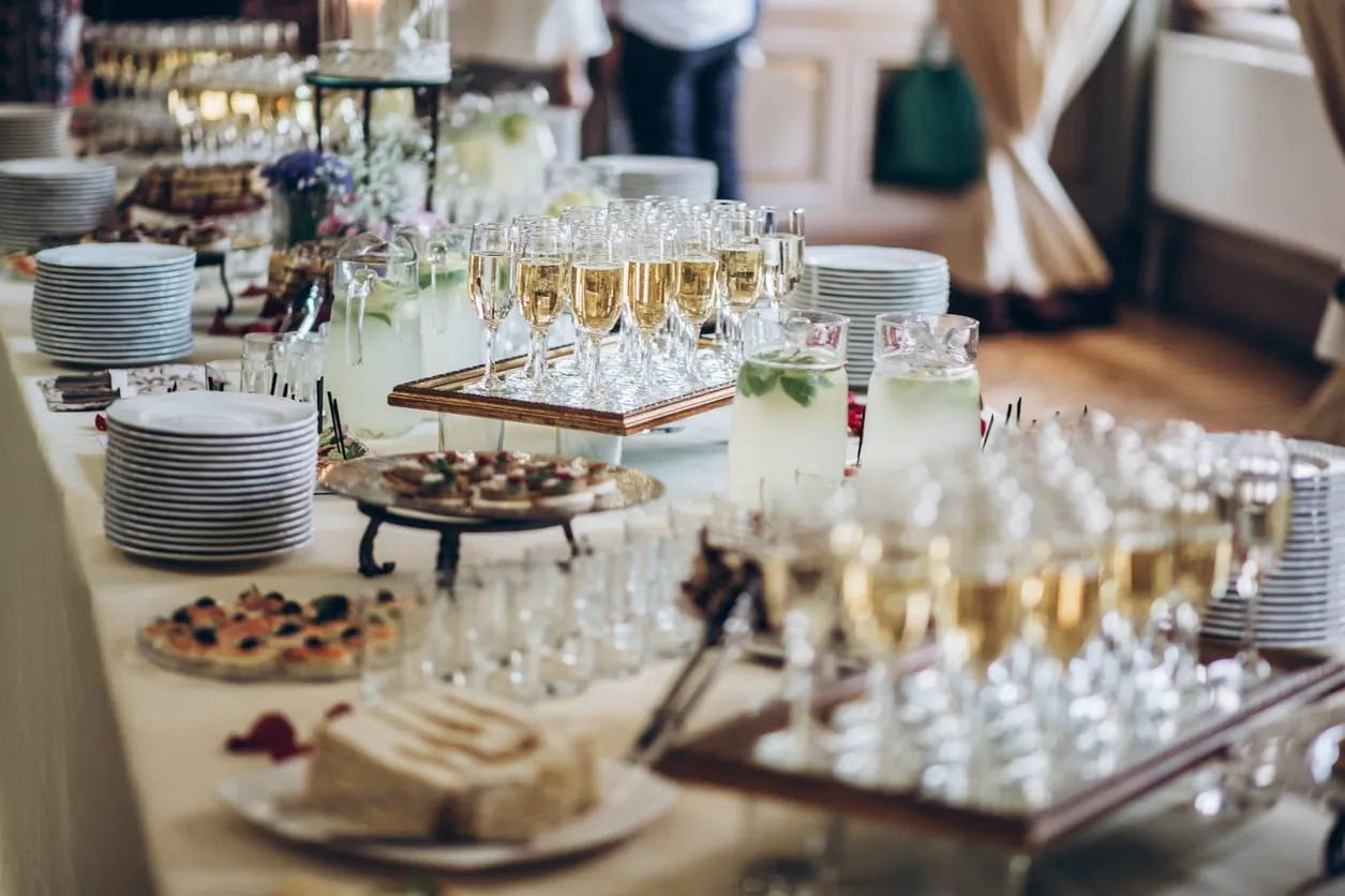 A catering table set with champagne glasses, canapes and stacked plates