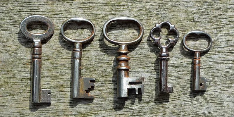 Five old metal keys laid out on weathered wood