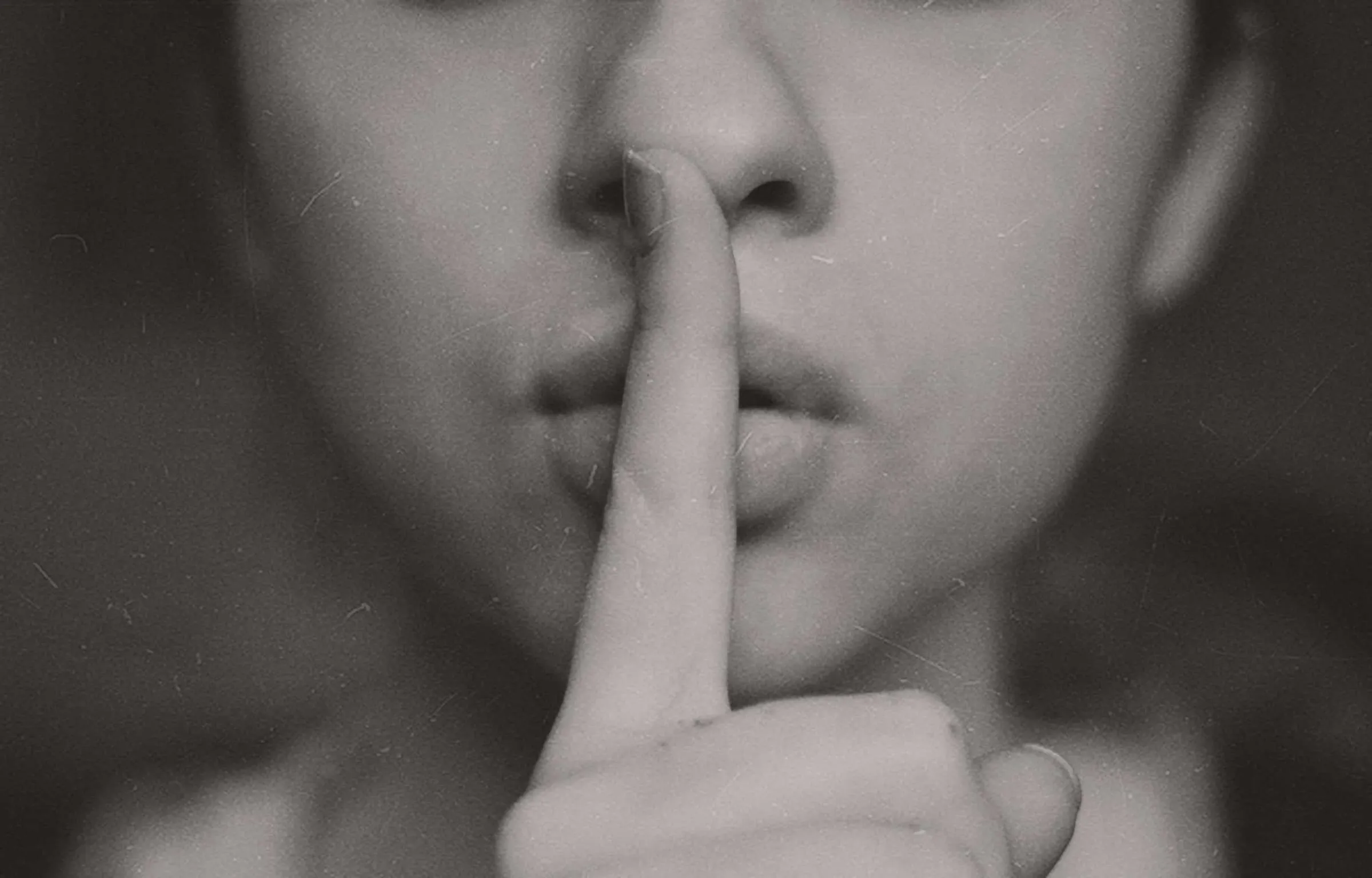 Black and white close view of a woman holding a finger to her lips