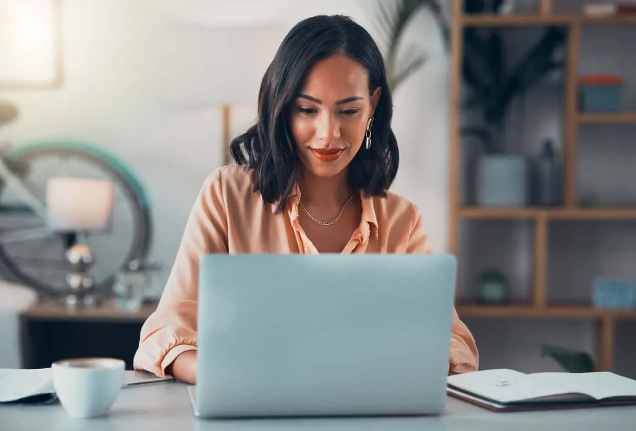 A woman working at a laptop at a desk at home