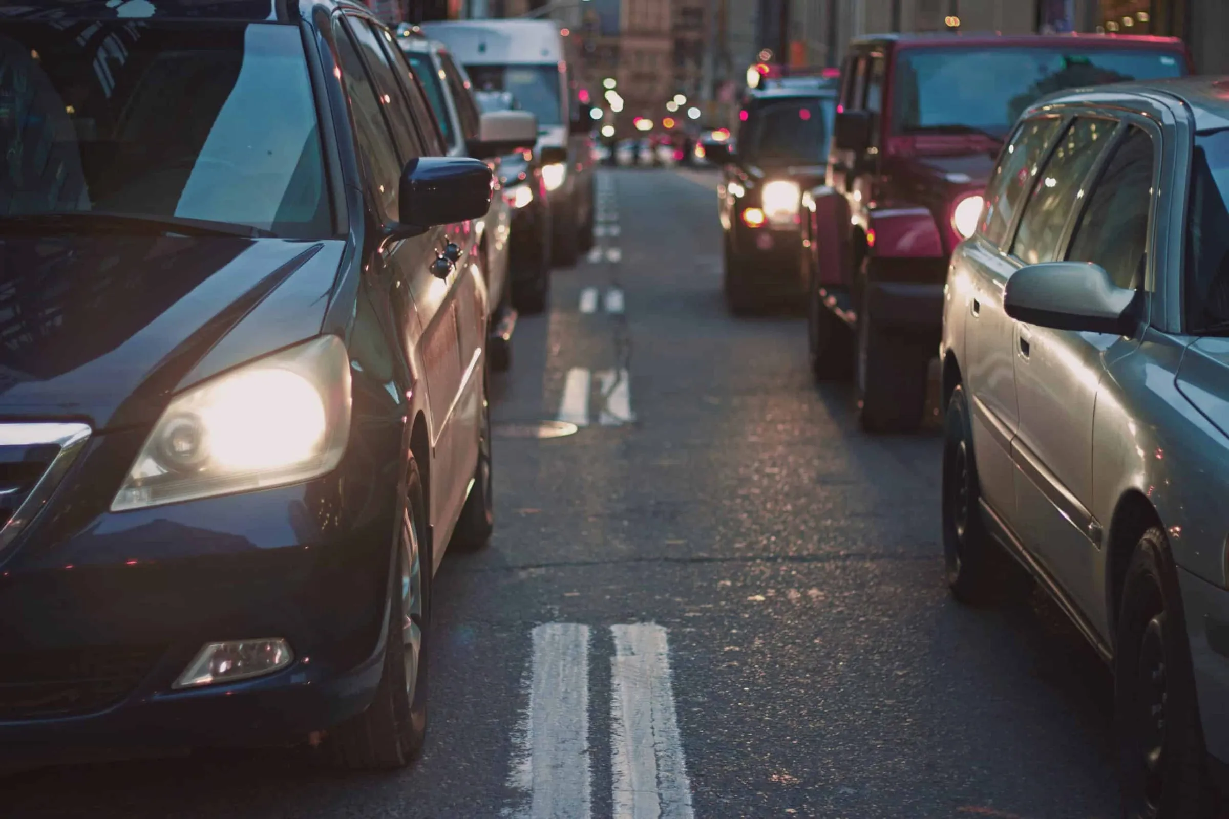 Cars stopped in heavy traffic at dusk with their headlights on
