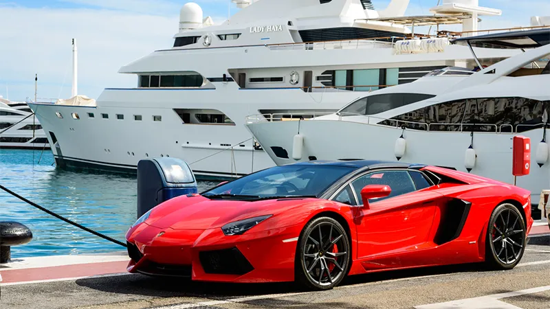 A red sports car parked on a quay in front of moored yachts