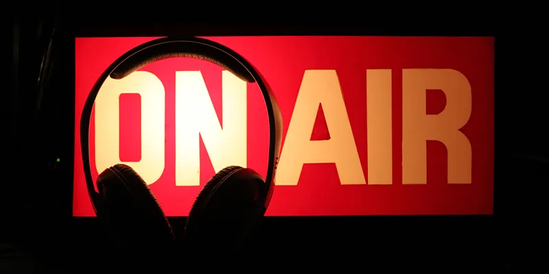 A red on air sign lit above a pair of headphones