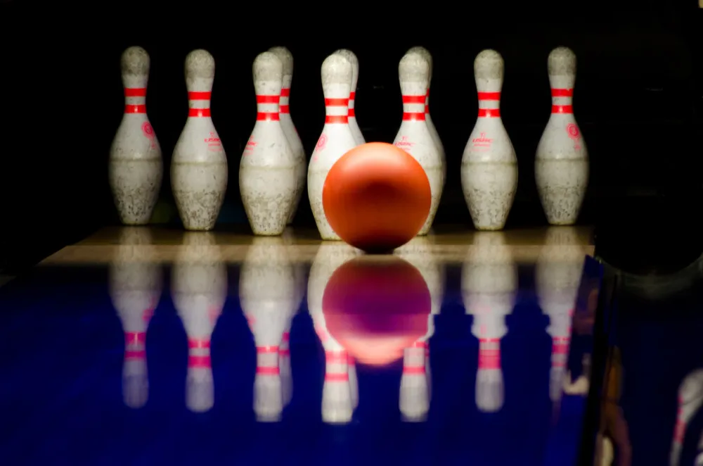 An orange bowling ball in front of a set of pins