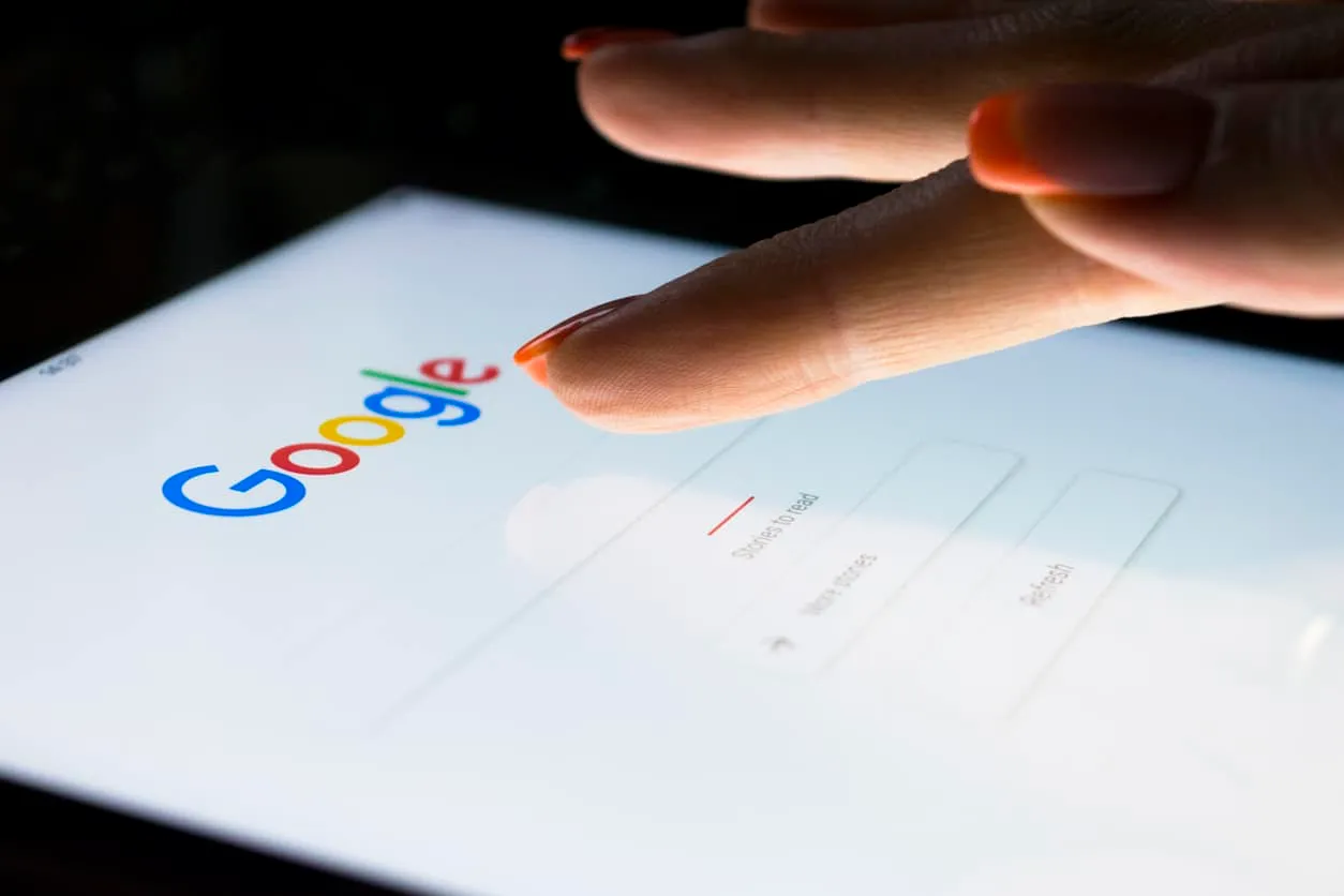 A finger touching the Google search page on a tablet