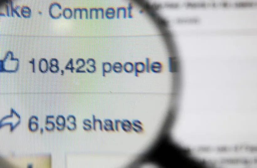 A magnifying glass held over a social post showing 108,423 likes and 6,593 shares