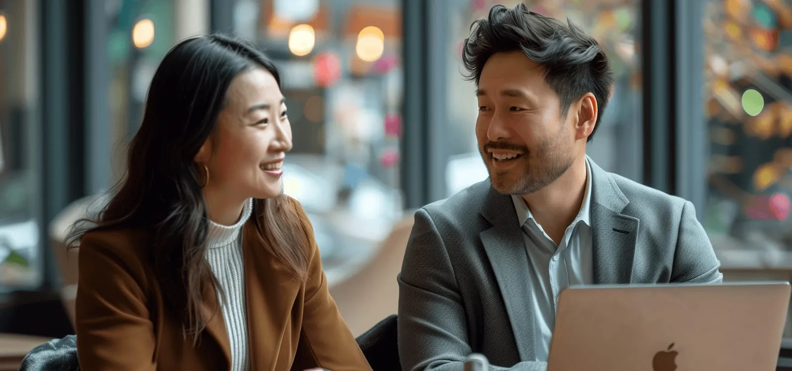 Two colleagues talking and smiling over a laptop