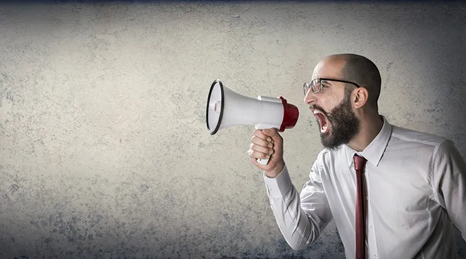 A man in a shirt and tie shouting into a megaphone